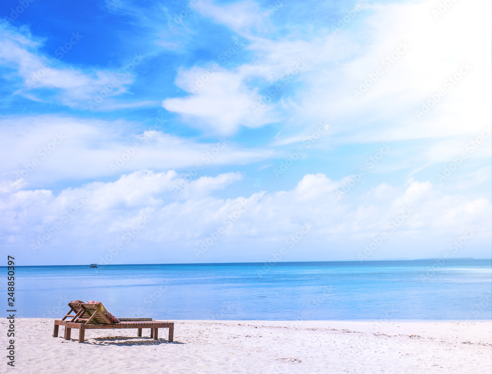 Fototapeta premium Chairs on the amazing beautiful sandy beach near the ocean with blue sky. Concept of summer leisure calm vacation for a tourism idea. Empty copy space, inspiration of tropical landscape