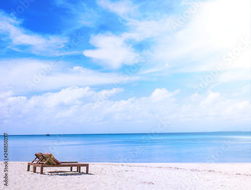 Chairs on the amazing beautiful sandy beach near the ocean with blue sky. Concept of summer leisure calm vacation for a tourism idea. Empty copy space  inspiration of tropical landscape