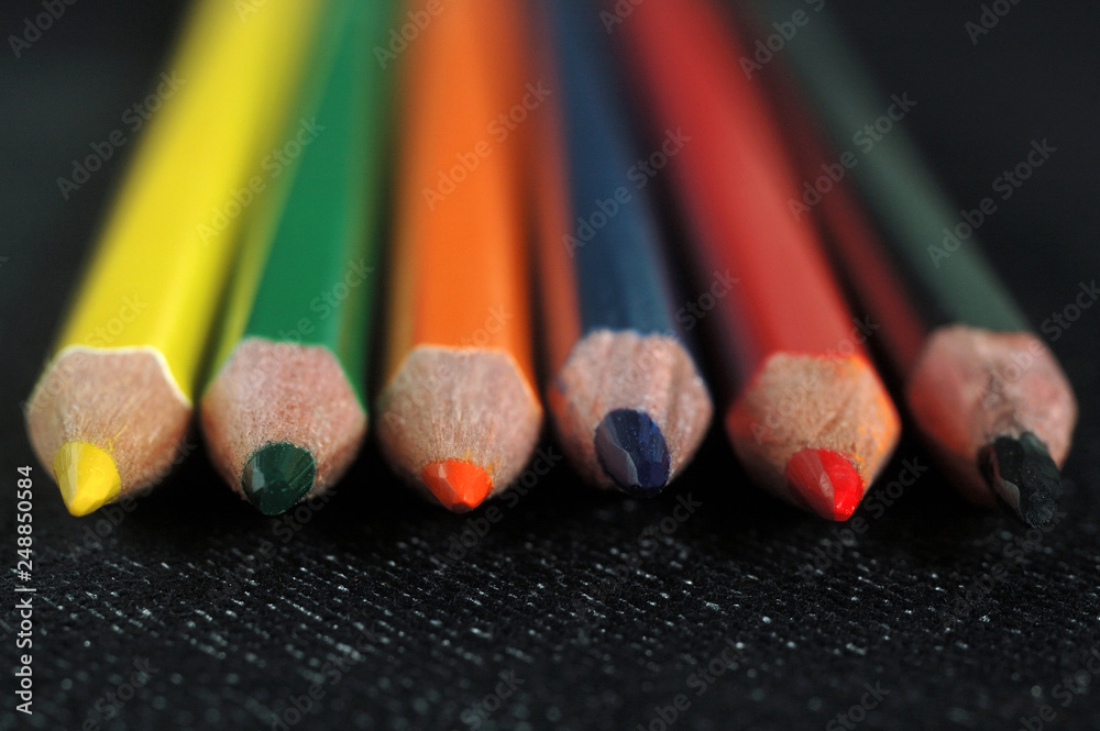 Colored pencils on a dark fabric background. Shallow depth of field Colored pencils on a dark fabric background. Shallow depth of field