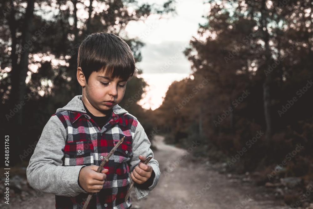 Child playing with a branch from a tree in the field. Happy kid playing in the field. Child playing with a branch from a tree in the field. Happy kid playing in the field.