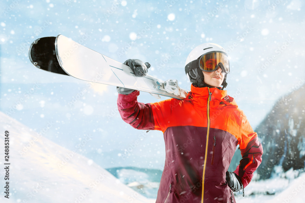 Female skier standing with skies in one hand on beautiful mountain landscape background. Winter, ski, snow, vacation, sport, leisure, lifestyle concept