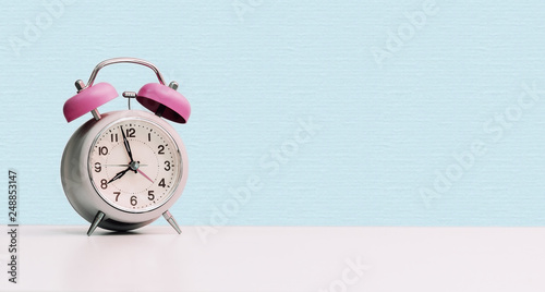 Retro styled white alarm clock, isolated and copy space, pink blue