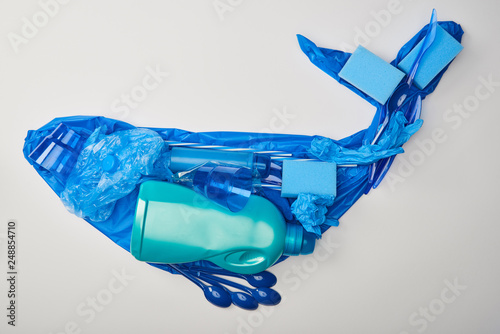 top view of whale figure made from rubber gloves, disposable plastic tableware, bag, sponges and bottle isolated on white photo