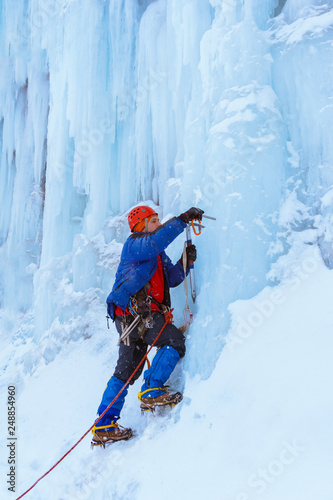 rock climber screwing ice screw into glacier surface