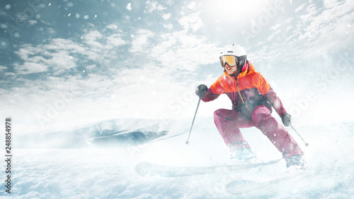Young beautiful athlete woman doing winter sport - she is skiing against white alps mountain background
