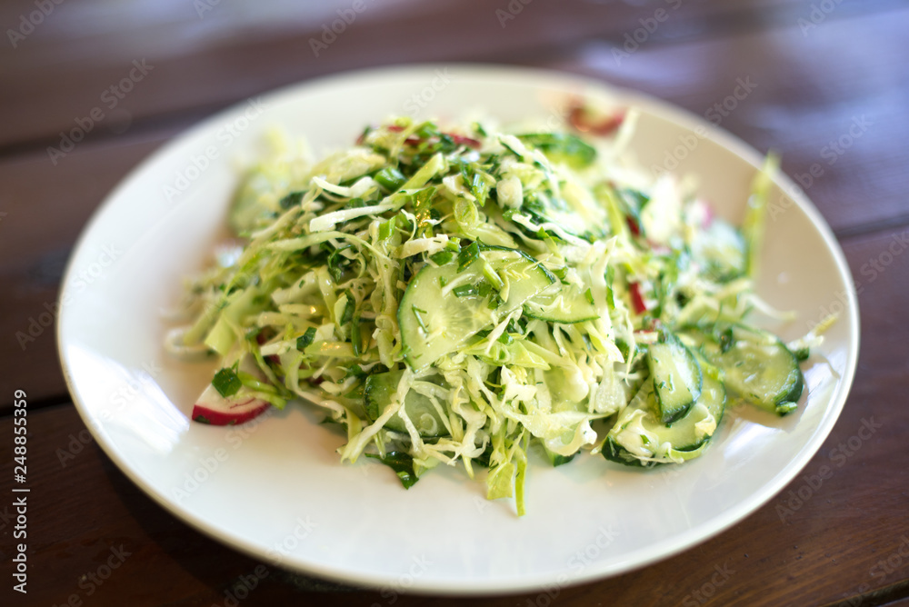 spring salad with cabbage cucumbers and radishes on a wooden background. spring salad with cabbage cucumbers and radishes on a wooden background.