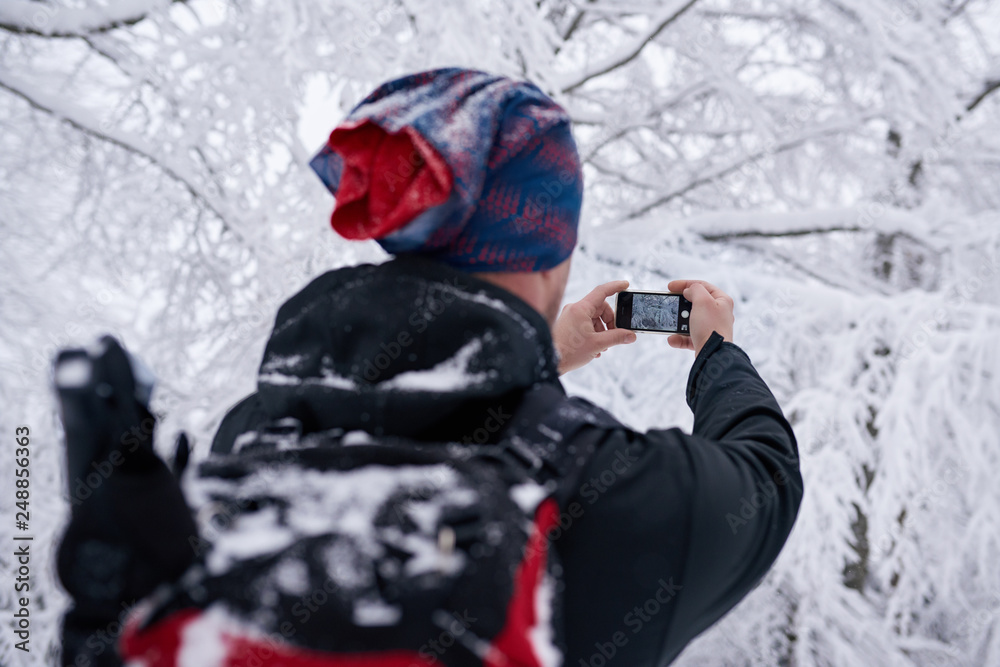 Hiker taking photos of a snow covered forest in winter Hiker taking photos of a snow covered forest in winter