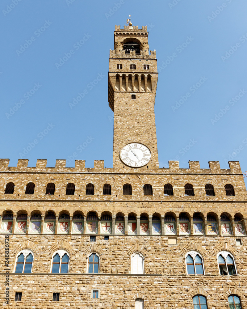 Color DSLR image of the historic landmark Tower of the Palazzo Vecchio, Florence, Italy, against a blue sky. Vertical with copy space for text