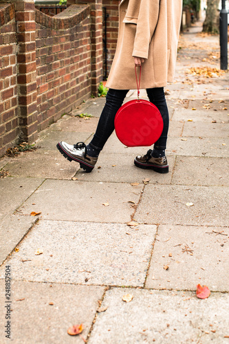 Unrecognisable stylish woman standing outdoors and holding round red velvet purse. photo