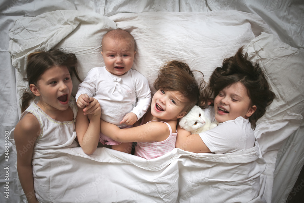 group of kids and an embracing cat sleeping on bed