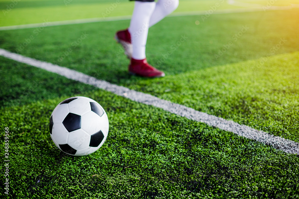 Obraz premium football on green artificial turf with soccer player speed run