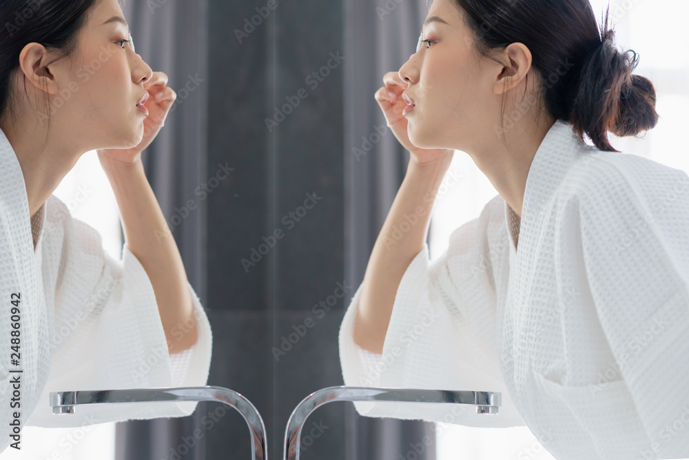 Fototapeta premium beautiful asian woman bare skin in white bathrobe wash and clean facial with care in morning freshness sunlight