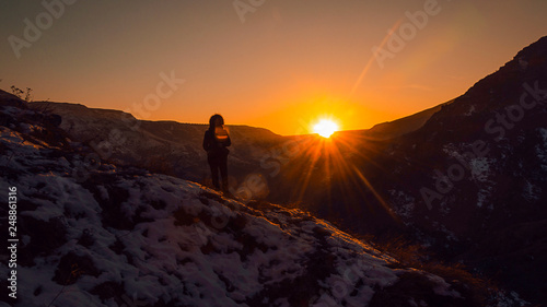 una persona in montagna guarda tramonto