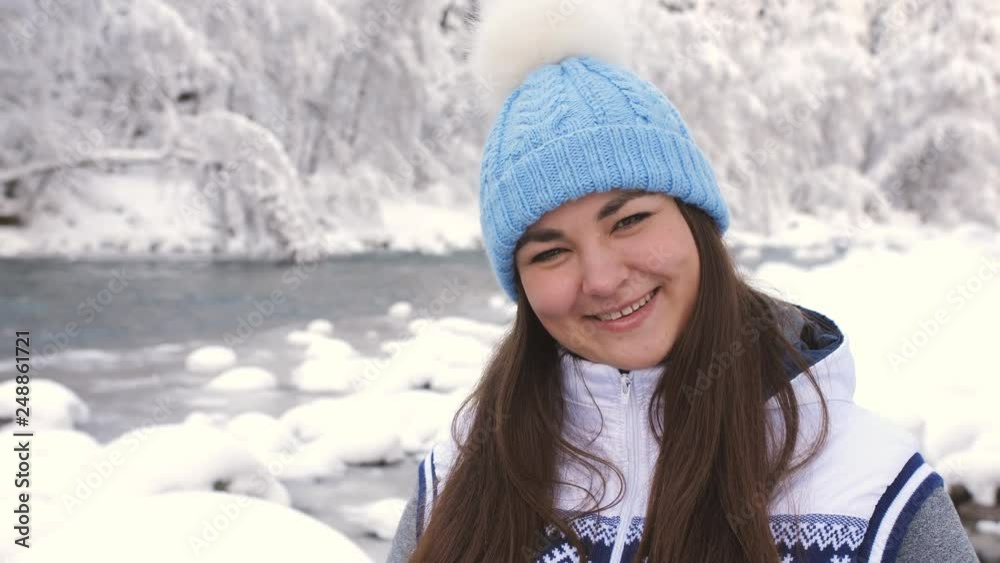 Portrait of beautiful woman in winter forest near a mountain river. The girl looks into the camera smiling and laughing. Portrait of beautiful woman in winter forest near a mountain river. The girl looks into the camera smiling and laughing.