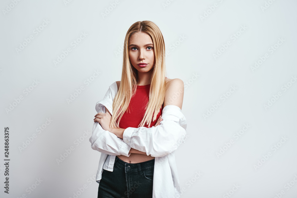 Something in the way she looks...Close-up studio portrait of gorgeous blonde woman keeping arms crossed and looking at camera. Beauty concept Something in the way she looks...Close-up studio portrait of gorgeous blonde woman keeping arms crossed and looking at camera. Beauty concept