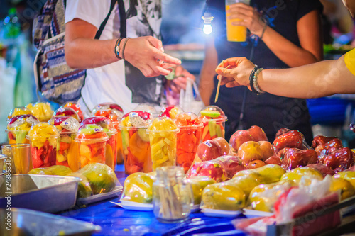 Close up street fruit vendor selling mixed fruits at Khao San Road night market, Bangkok, Thailand.