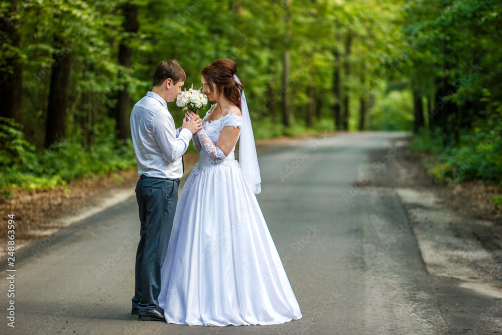 Bride and groom stand on the road in green forest. Wedding photography. Bride and groom stand on the road in green forest. Wedding photography.