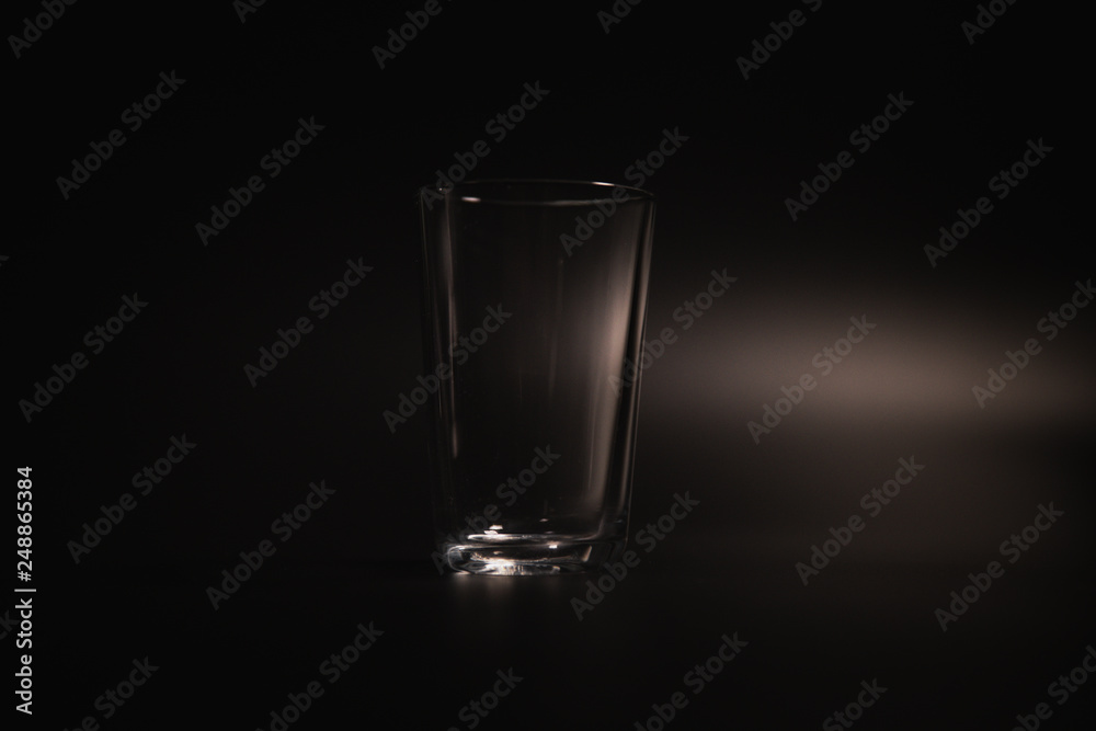 Water is poured into a transparent glass on a dark background Water is poured into a transparent glass on a dark background