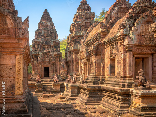 Banteay Srei temple golden in cambodia with statues and a look to an entry
