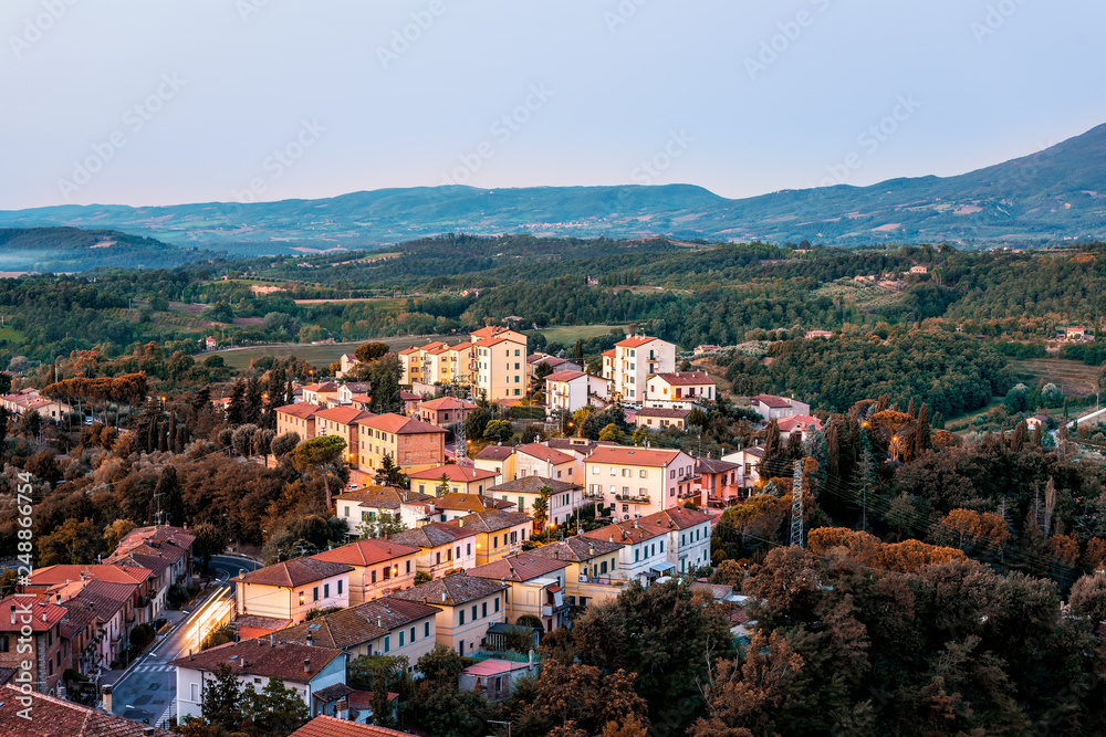 Chiusi village vintage cityscape at sunrise in Umbria Italy with streets and rooftop houses on mountain countryside and rolling hills with brown foliage trees