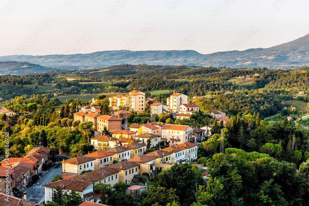 Chiusi village cityscape at golden sunrise in Umbria Italy street road cars and rooftop houses on mountain countryside and rolling hills