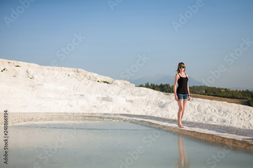 Natural travertine pools and terraces in Pamukkale. Cotton castle in southwestern Turkey, girl standing in natural pool. A woman in the pool of thermal springs and travertine 