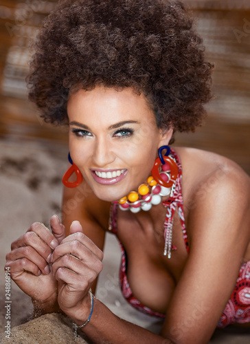 Beauty portrait of natural girl with afro playing with sand