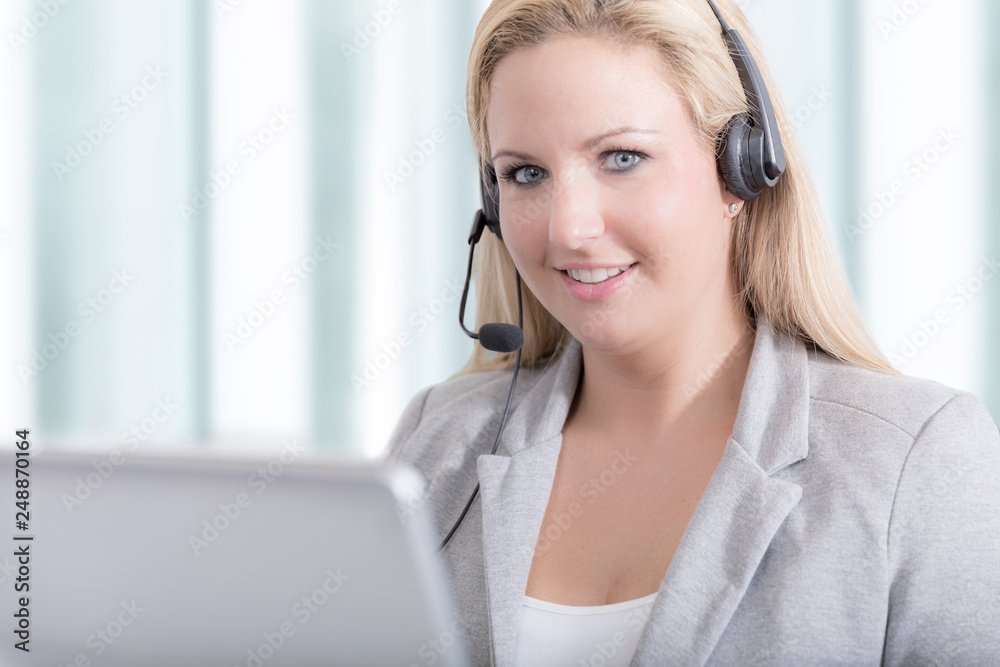 Hübsche Hotline Mitarbeiterin mit Headset im Call Center lächelt Hübsche Hotline Mitarbeiterin mit Headset im Call Center lächelt