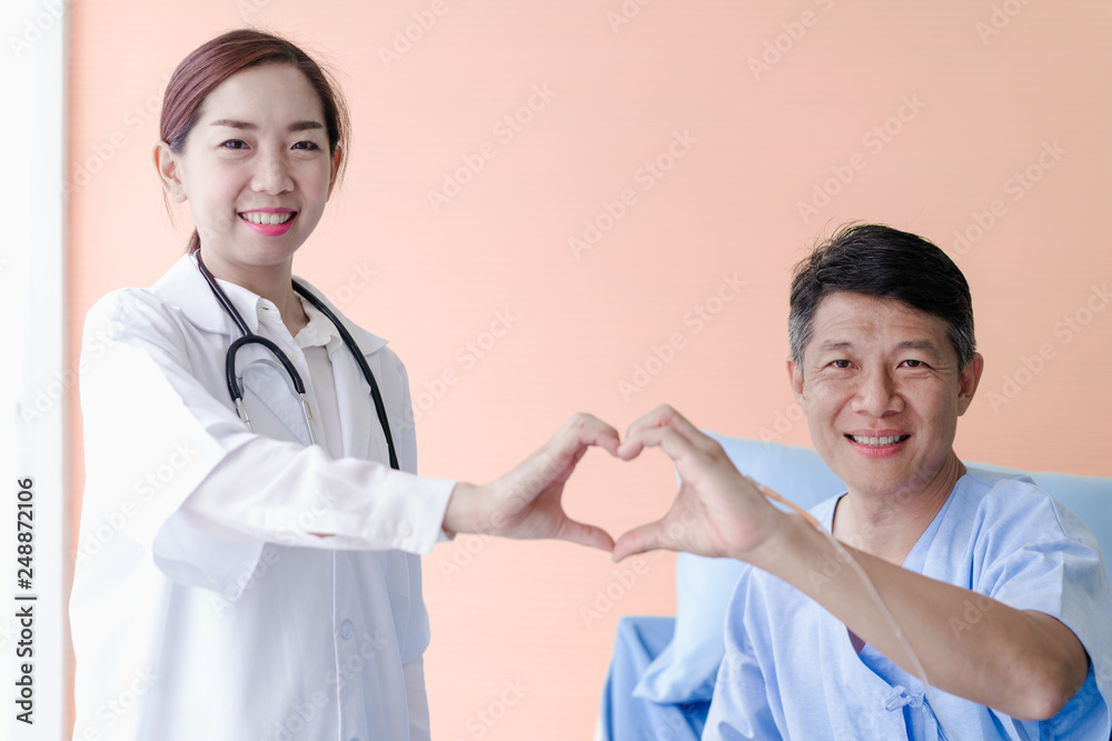Asian woman doctor makes heart sign with hands to patient man Asian woman doctor makes heart sign with hands to patient man