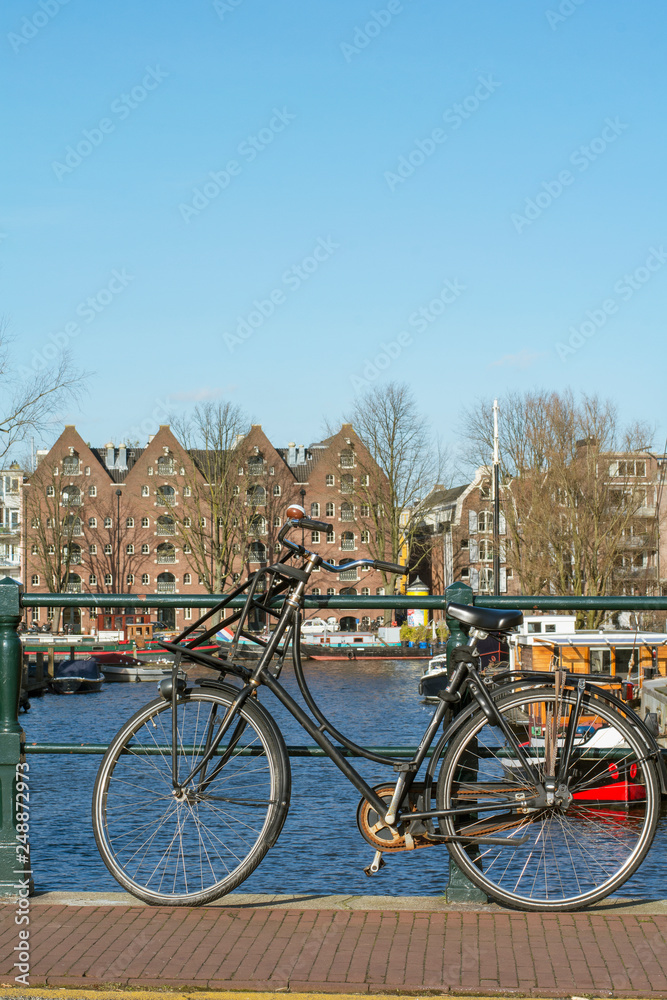 One usual black bike near the canal in the center of Amsterdam in the sunny autumn day