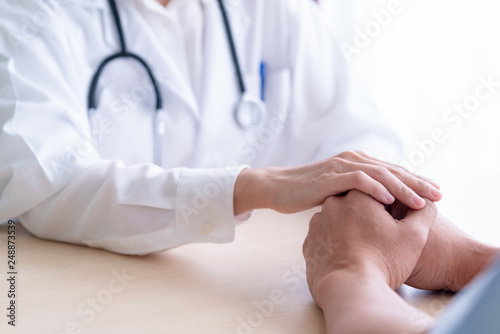 Woman doctor holds hands for male patients to encourage.