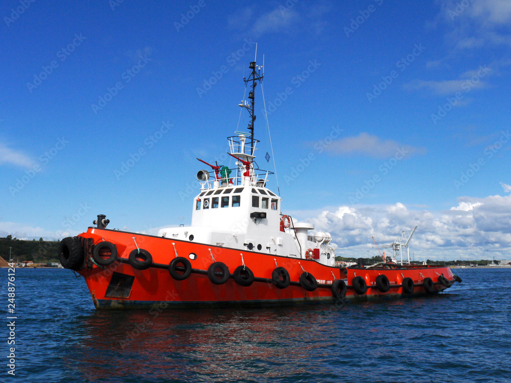 Red Tug at anchor in estuary bay awaiting next towing operation.