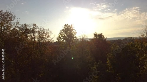 Drone footage rising above the fall colored tree tops revealing a view of The Blue Mountains, Ontario. photo