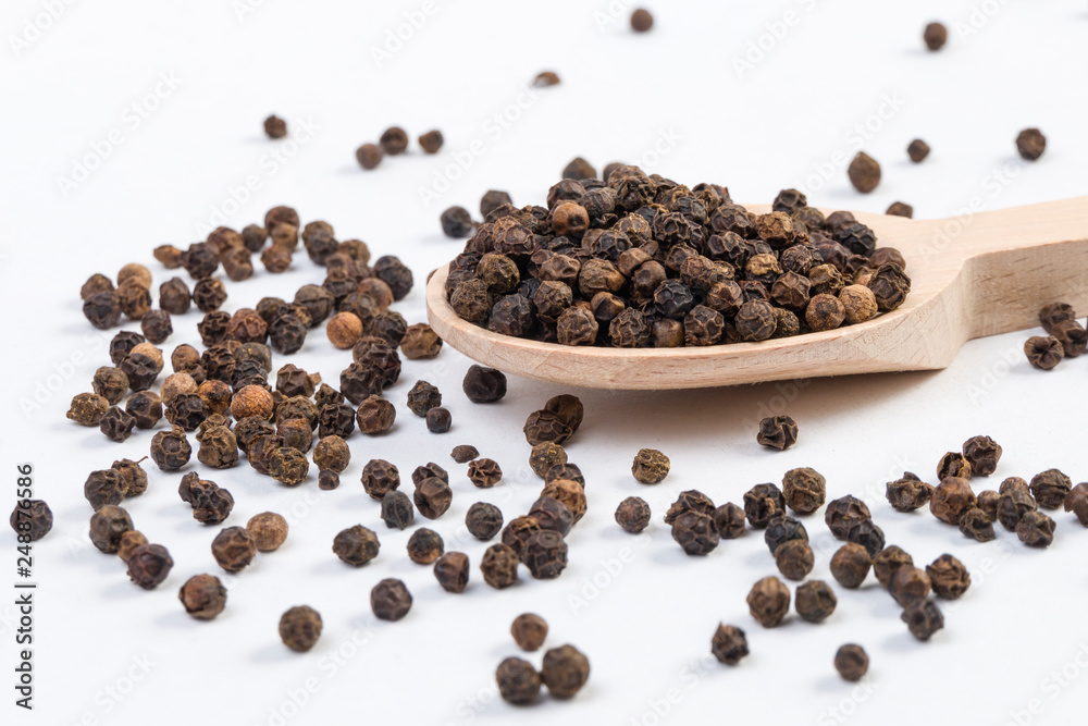 blask pepper peppercorns in wooden spoon isolated on white background. Closeup. blask pepper peppercorns in wooden spoon isolated on white background. Closeup.