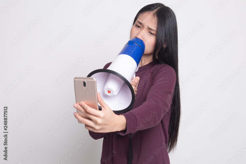 Obraz premium Angry young Asian woman shout with megaphone to mobile phone.