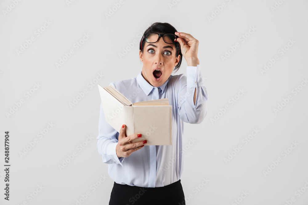 Photo of surprised female worker wearing eyeglasses reading book in the office, isolated over white background Photo of surprised female worker wearing eyeglasses reading book in the office, isolated over white background