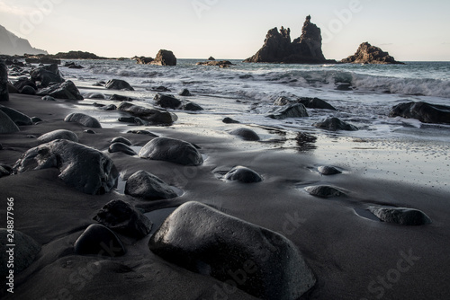 Black beach with wet stones in foreground
