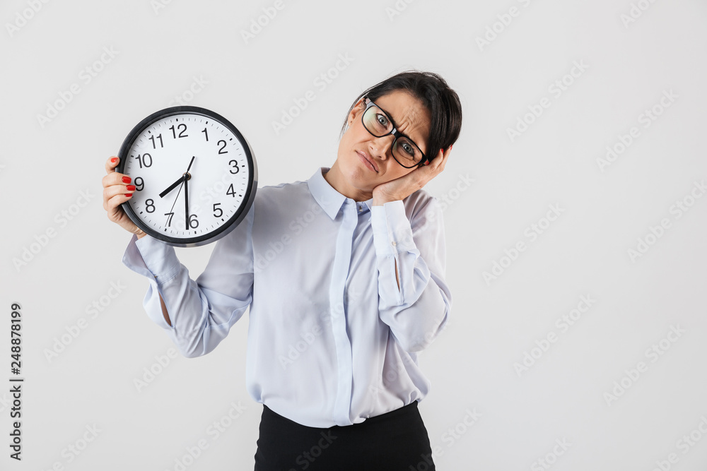 Portrait of european businesswoman wearing eyeglasses holding round clock in the office, isolated over white background Portrait of european businesswoman wearing eyeglasses holding round clock in the office, isolated over white background