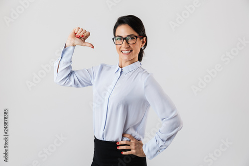Image of successful secretary woman wearing eyeglasses standing in the office, isolated over white background