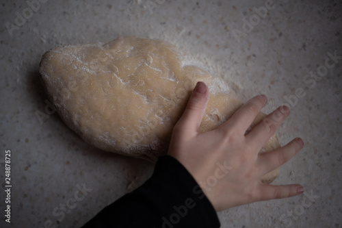 Dłoń na cieście surowym posypanym mąką 