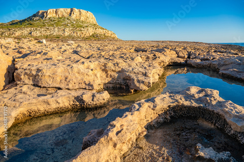 Beautiful landscape with reflection of rocks in the water. Ayia Napa coastline at sunset. Cape Greco National Forest Park, Cyprus.