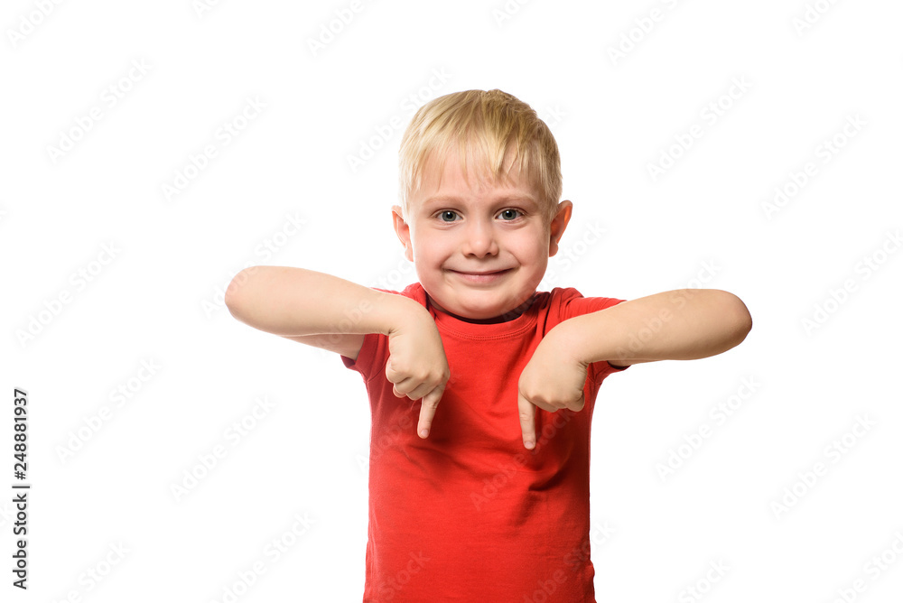 Smiling little blond boy in a red shirt stands and shows index fingers down. Isolate on white background. Smiling little blond boy in a red shirt stands and shows index fingers down. Isolate on white background.