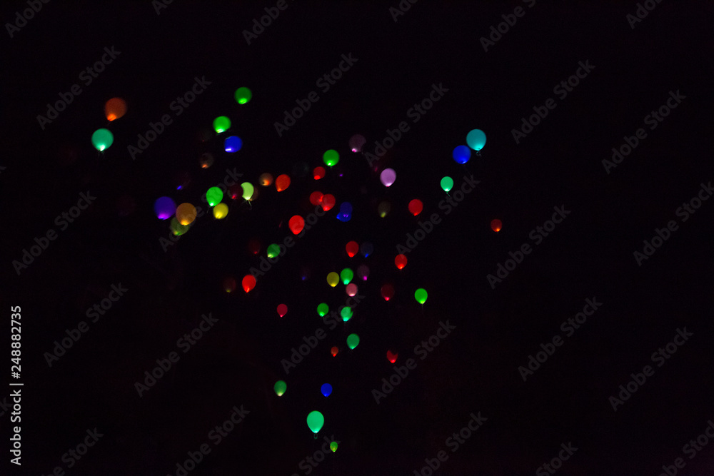 Colorful, glowing Balloons Flying in the Dark Night Sky.