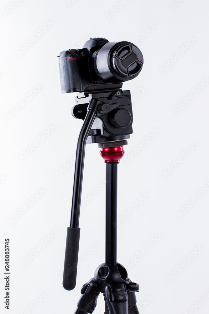 Small camera tripod on white background. Camera on tripod. Professional photographic equipment.