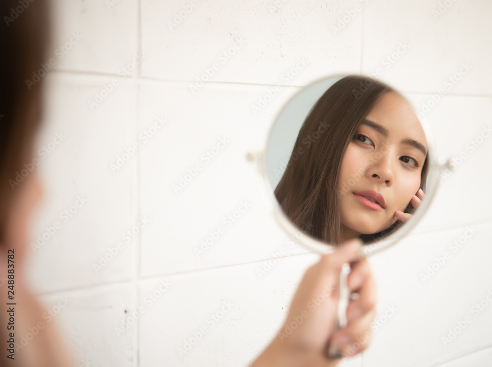 portrait of young woman in bathroom looking at mirror 