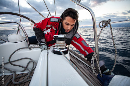 Young sailor guy sets sail on a boat.