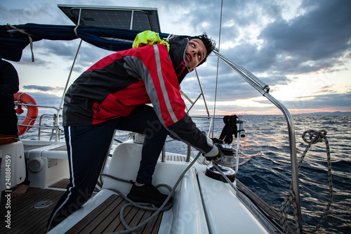 Young sailor guy sets sail on a boat.