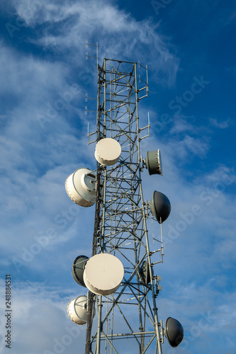Radio communcations tower isolated against a blue sky with clouds photo