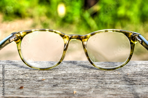 Reading glasses in a plastic frame on a rough wooden surface against a grain background