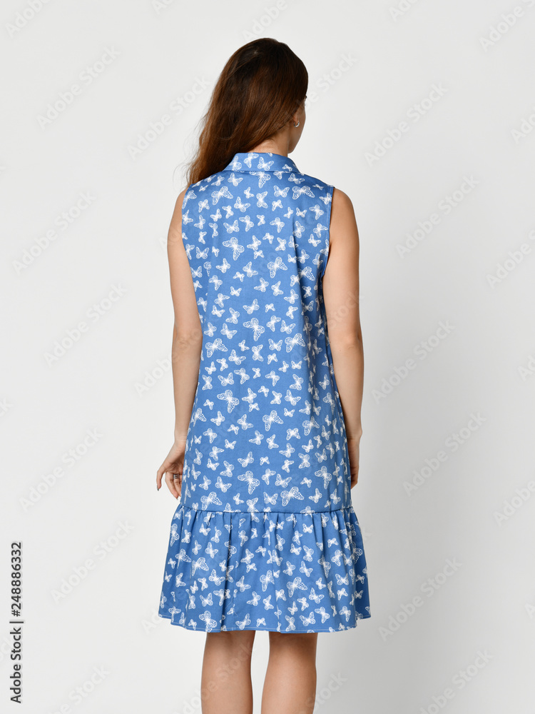 Young beautiful woman posing in new blue stripes casual summer dress on grey Young beautiful woman posing in new blue stripes casual summer dress on grey